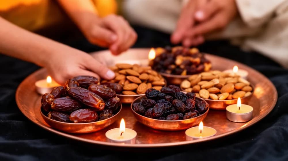 Des coupelles de fruits secs et de sucreries sur un plateau de cuivre, entourées de bougies