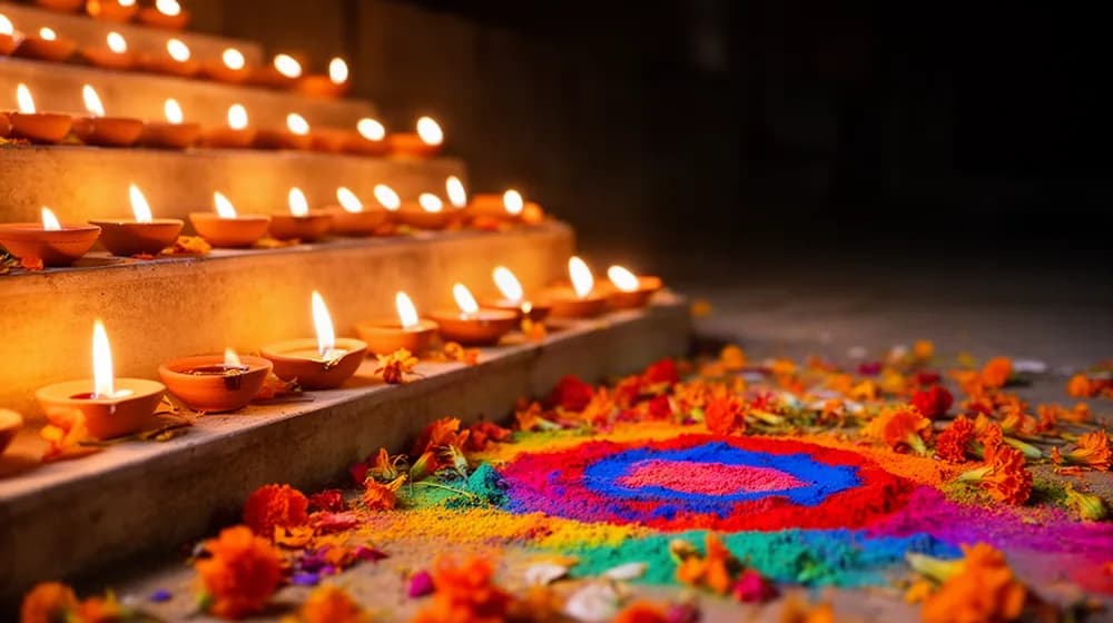 Des dizaines de petites lampes à huile allumées autour d’un motif de poudres colorées, la nuit